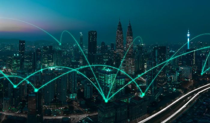 An aerial photo of a city at sunset with an overlayed image of connected lines representing a connected wireless network
