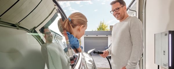 Mężczyzna ładujący swój samochód elektryczny Tesla za pomocą kabla ładowania NACS z ładowarki naściennej