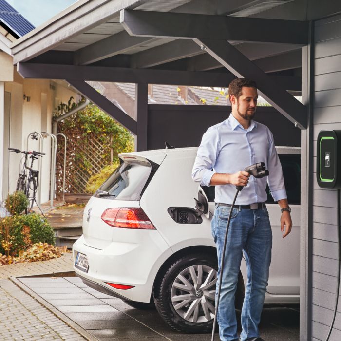 Person charging an electric car at home with a home charger