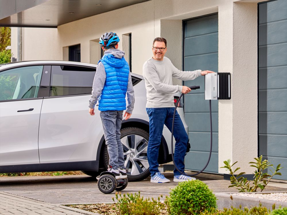 Une personne charge sa voiture électrique Tesla sur une borne de recharge murale à l'aide d'un câble de charge NACS