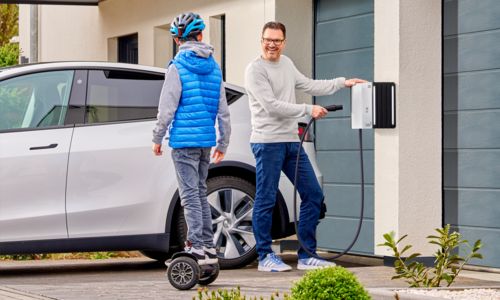 Man charges his Tesla electric car using a NACS charging cable on the wallbox