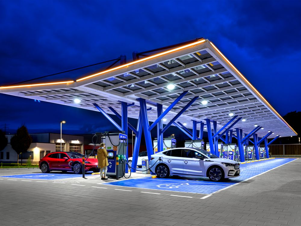 Electric cars being charged in the evening at an illuminated fast charging park