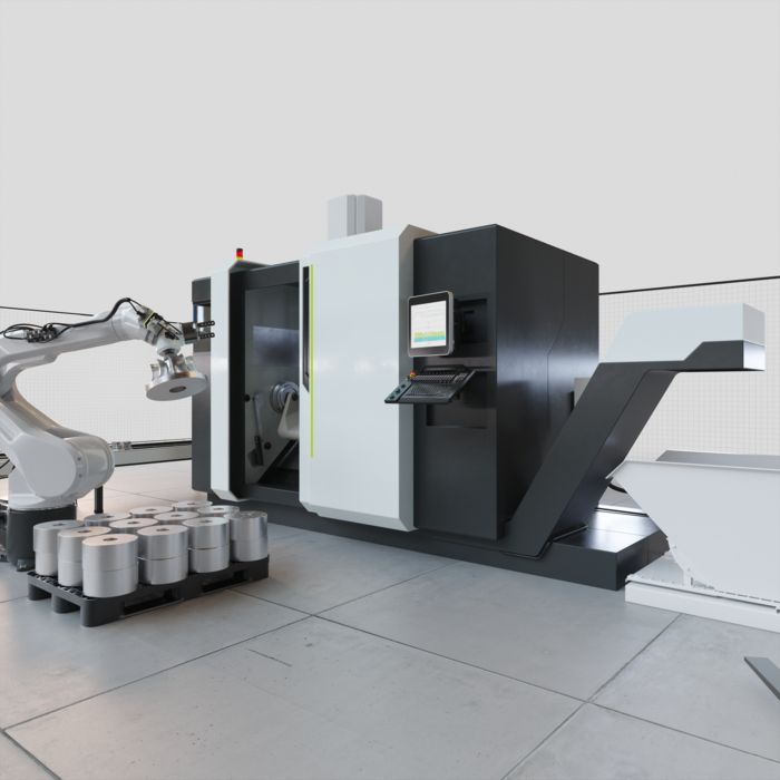 Une machine-outil avec un espace de travail ouvert et, à droite, un pupitre de commande. L'alimentation des pièces brutes par le bras du robot et le convoyeur de copeaux sont également visibles.