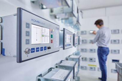 Man in front of several protective devices in a power station
