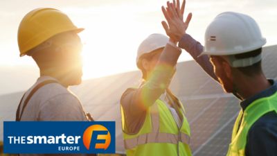 Employees in solar park with Smarter E logo