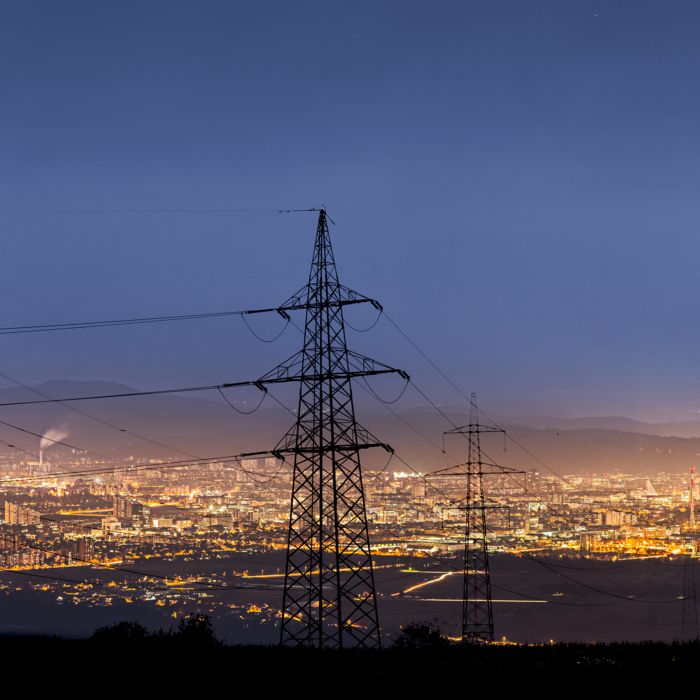 Electricity pylons in front of an illuminated city