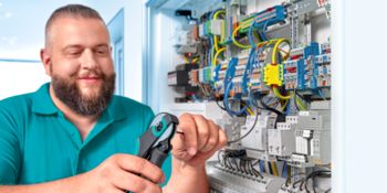 Installer at the control cabinet with crimping pliers in hand