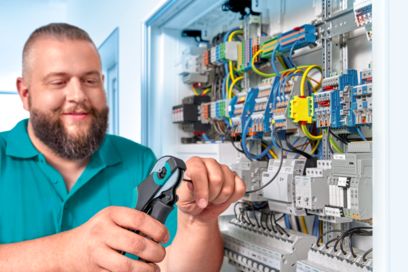 Man with a tool in front of a control cabinet during electrical installation
