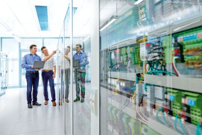 People in front of a control cabinet discussing the system integration