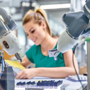 Robot collaboratif dans la fabrication de produits avec une femme en arrière-plan