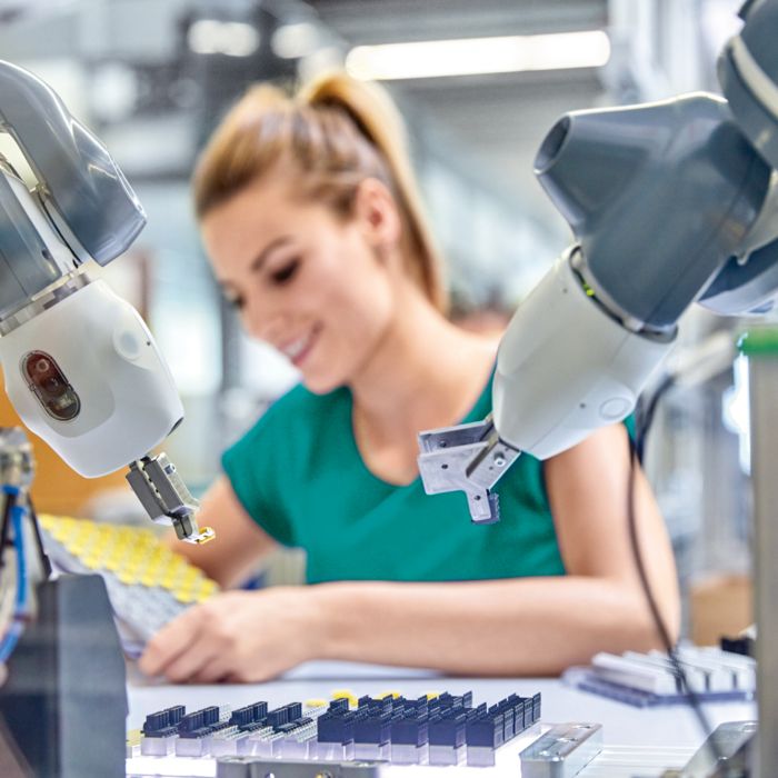 Robot collaboratif dans la fabrication de produits avec une femme en arrière-plan