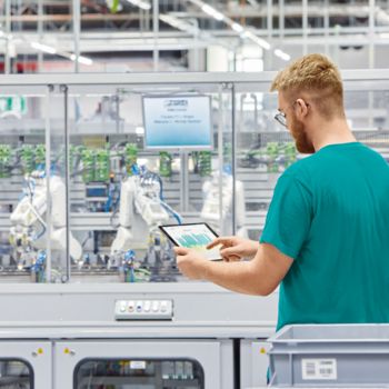 Un collaborateur de Phoenix Contact avec un iPad et un robot sur une chaîne de production industrielle