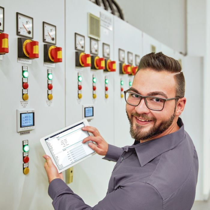 Persona con tablet davanti al dispositivo per la misurazione dell'energia EMpro, installato nello sportello del quadro elettrico del sottoquadro di distribuzione