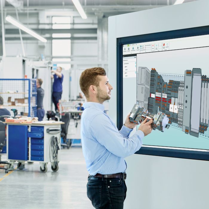 Person in production with a terminal strip in hand looking at the screen with the clipx ENGINEER engineering software