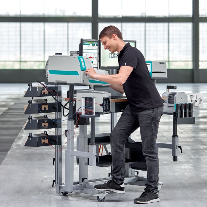 Person standing in front of the clipx WIRE assist worker assistance system, marking a wire with a printing system