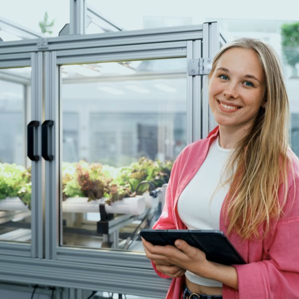 Duale Studentin lehnt an einem Vertical Farming Gewächshaus