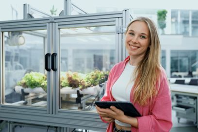 Duale Studentin lehnt an einem Vertical Farming Gewächshaus