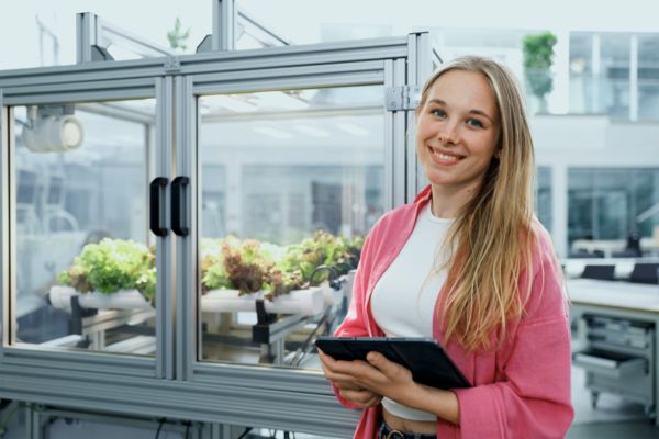 Duale Studentin lehnt an einem Vertical Farming Gewächshaus