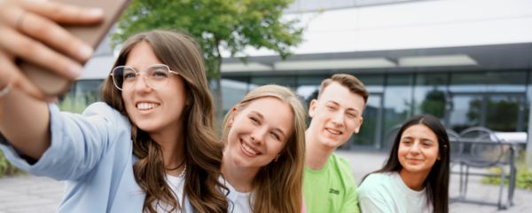 Junge Mitarbeitende sitzen zusammen und unterhalten sich