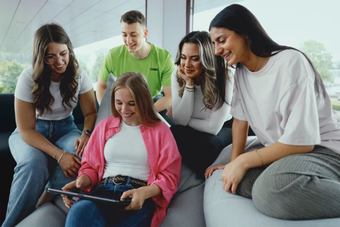 Chicas y un chico mirando a una pantalla de un portátil