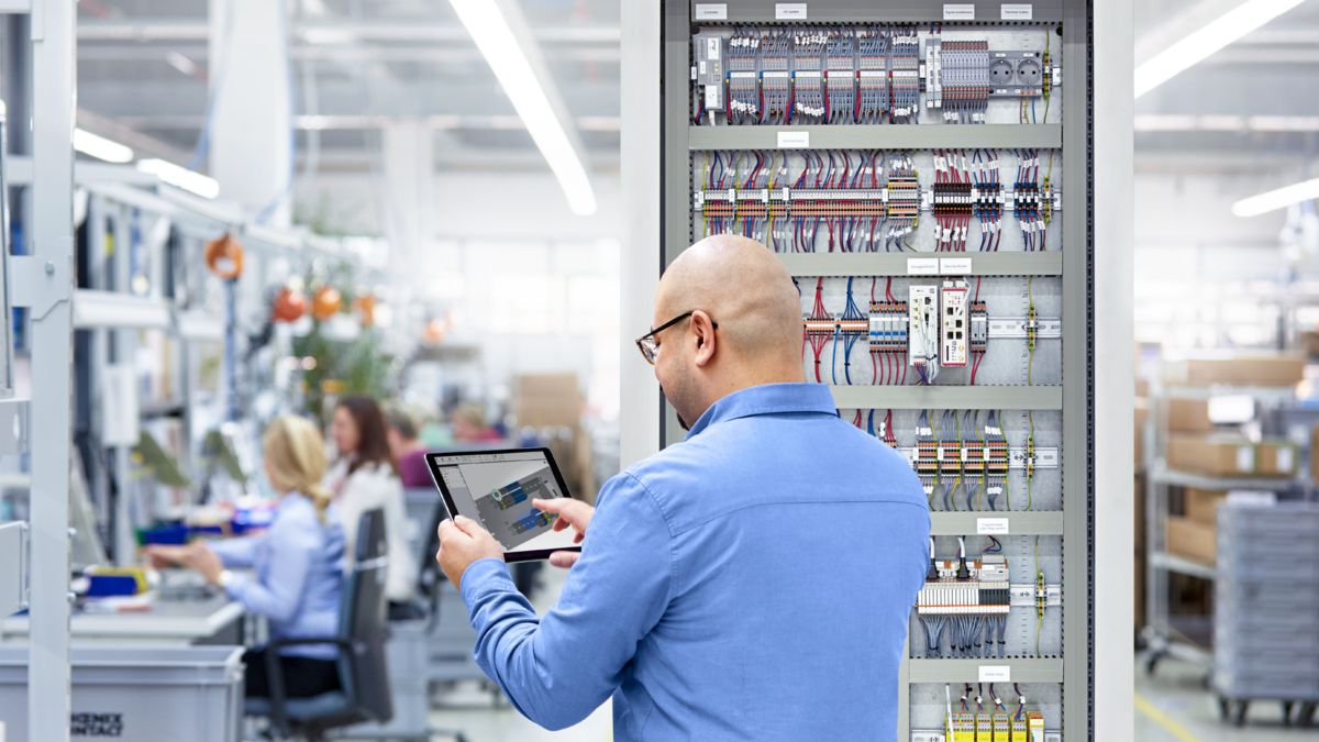 Person bedient Tablet vor einem Schaltschrank