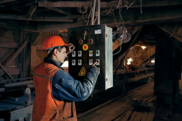 Person im Bergbau bedient gekennzeichnete Taster an einem Anschlusskasten