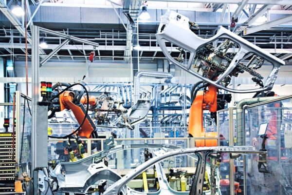 Robots colaboradores transportan un componente de la carrocería por una línea de producción