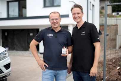 Portrait of two people in black polo shirts with KNX module in their hand