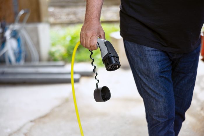 Une main tient un connecteur de charge