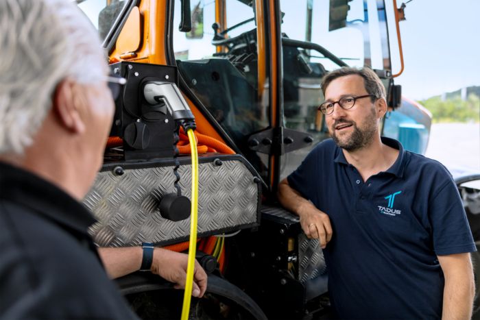Deux hommes se tiennent près d'un tracteur électrique
