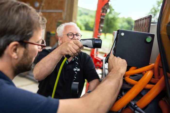 Un homme branche le connecteur de charge dans la prise d'un tracteur électrique
