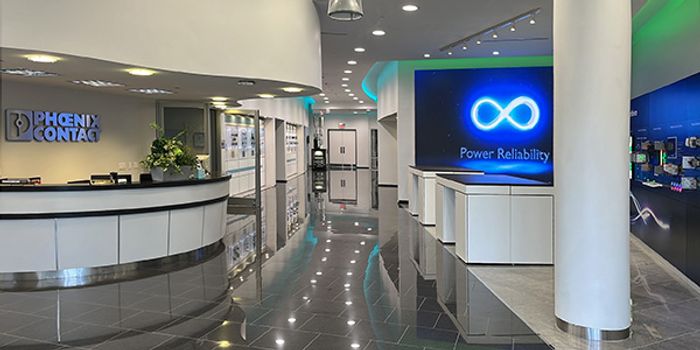 A photo taken inside the lobby of the Houston Customer Technology Center, showing a sleek modern design with a front desk to the left and display monitors to the right.