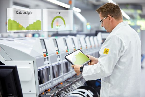 Employé de production devant une installation avec tablette et données de l'installation