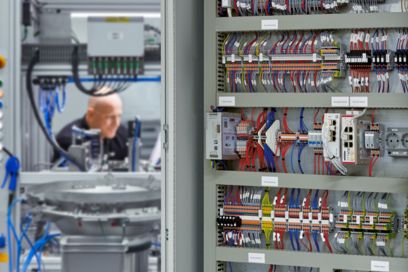 Person operating a machine with control cabinet in the foreground