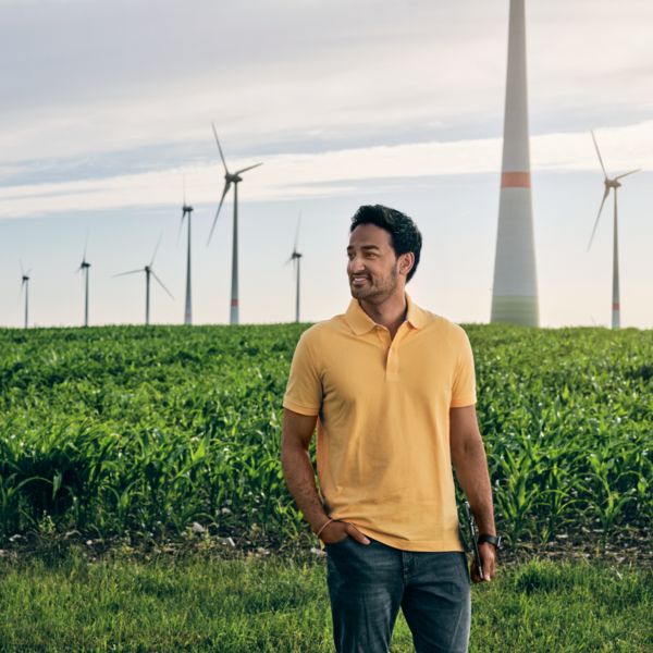 Ein Mann steht auf einem Feld vor Windrädern
