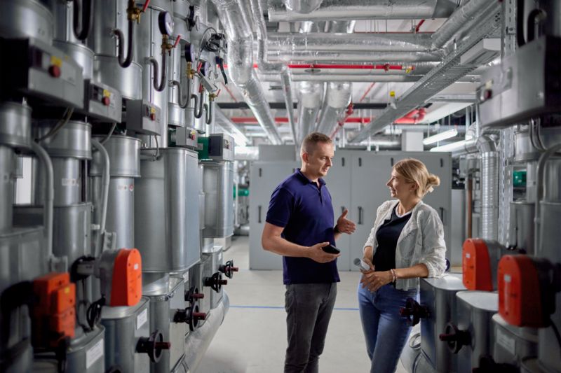 Two people talking in the plant room in the basement
