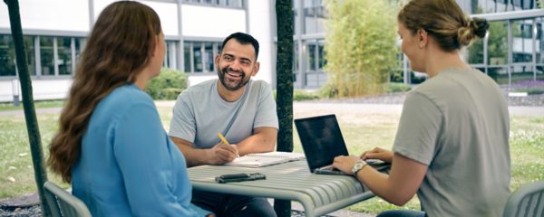Employees sitting in front of an office building working together