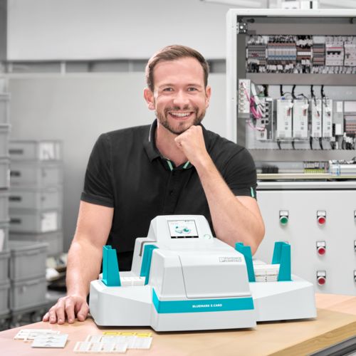 Person with the Bluemark&nbsp;E.Card UV inkjet printer in front of a control cabinet