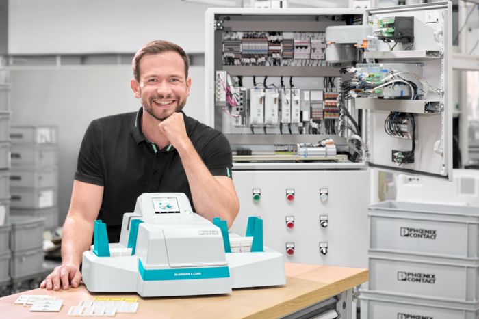 Person marking card materials with the UV inkjet printer at a workbench